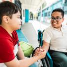 Un élève en fauteuil roulant salue un camarade de classe