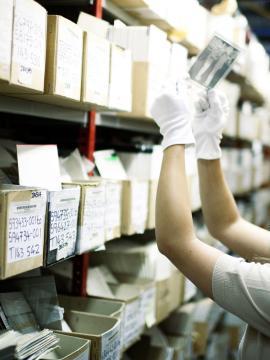 une femme observe une photographie dans un fonds d'archives