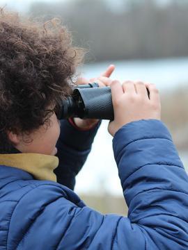 Un enfant observe la nature à travers des jumelles