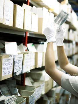 une femme observe une photographie dans un fonds d'archives