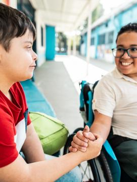 Un élève en fauteuil roulant salue un camarade de classe