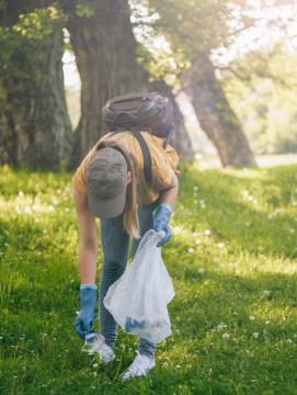 Une femme ramasse un déchet dans une forêt