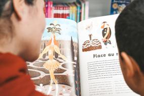 Un adulte et un enfant lisent un livre jeunesse