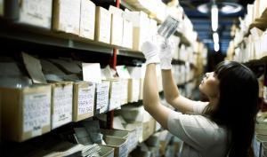 une femme observe une photographie dans un fonds d'archives