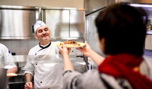 Un cuisinier sert un plat à la cantine