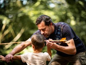 Un médiateur apprend à un enfant à tirer comme les hommes préhistoriques
