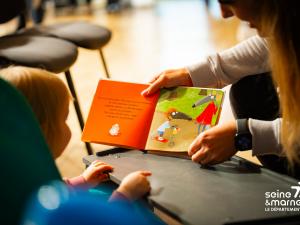 Un enfant lit un livre avec un parent