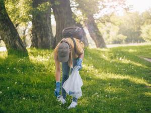 Une femme ramasse un déchet dans une forêt