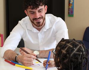 Hugo Issaly, référent de l'aide sociale à l'enfance, dessine avec une petite fille