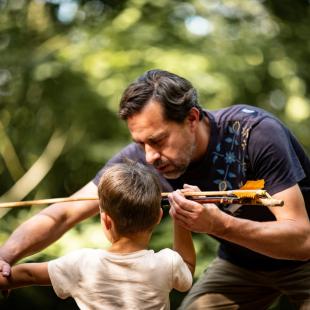 Un médiateur apprend à un enfant à tirer comme les hommes préhistoriques