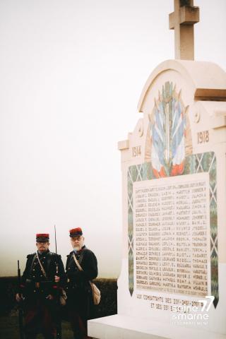 Deux hommes costumés en Poilus à côté d'une tombe de la Première Guerre mondiale