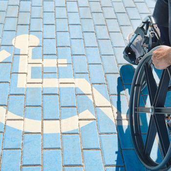 Une personne en fauteuil roulant sur une place réservée aux handicapés