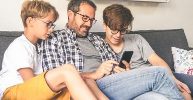 un père de famille avec ses deux garçons et son smartphone