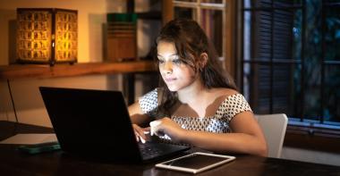 Une jeune femme devant son ordinateur le soir
