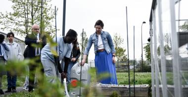 Un collégien arrose un potager à l'aide d'un récupérateur d'eau