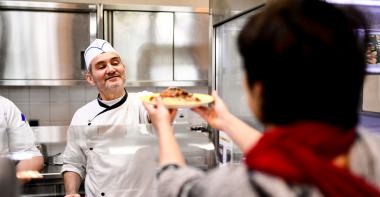 Un cuisinier sert un plat à la cantine