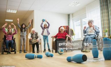 Des pesonnes âgées en fauteuil roulant jouent avec des jeunes enfants