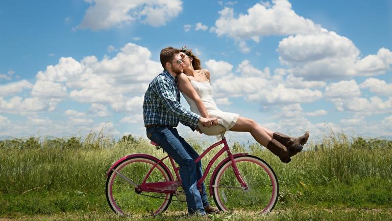 Deux jeunes sur un vélo qui s'embrassent