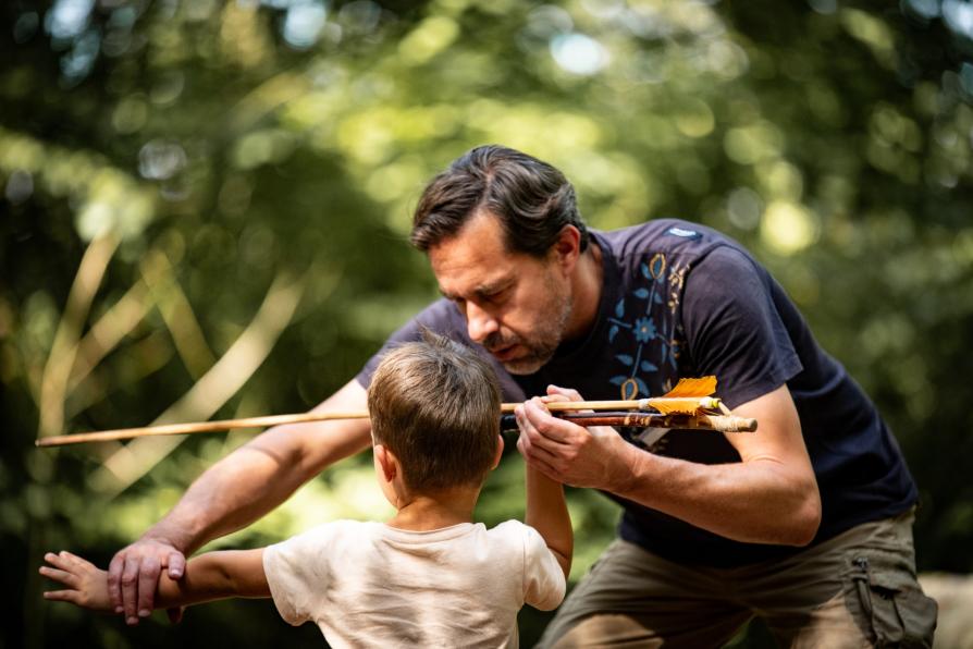 Un médiateur apprend à un enfant à tirer comme les hommes préhistoriques