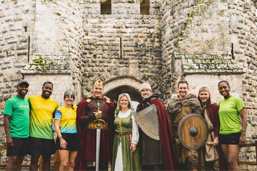 Des bénévoles et des coureurs devant un château fort