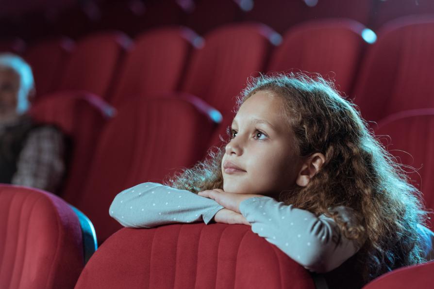 Une adolescente regarde un film au cinéma