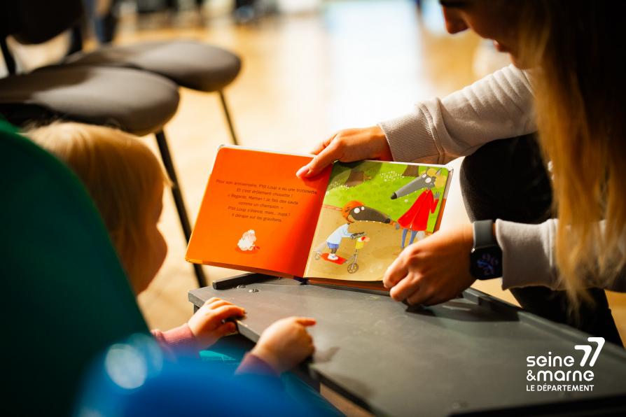 Un enfant lit un livre avec un parent